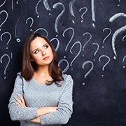 young woman with question marks on chalkboard in the background