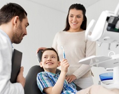 little boy holding a toothbrush in the dental chair