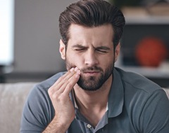 Man holding his cheek due to dental emergency in Oklahoma City