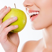Woman about to bite into a green apple