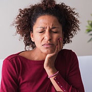 Woman in maroon who is experiencing a toothache
