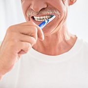 Man with mustache brushing his teeth