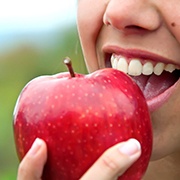 Closeup of patient with dental implants in Flint eating an apple
