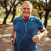 Man with dental implants in Flint smiling and jogging to stay healthy