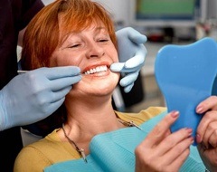 Woman looking at new dentures in mirror