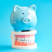 light blue piggy bank sitting on top of a set of false teeth