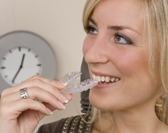 Young woman smiling and holding invisalign aligner