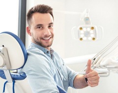 man giving thumbs up in dental chair