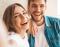 Younger couple smiling with Lumineers while standing outside