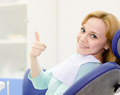 Woman in dental chair smiling with her thumb up