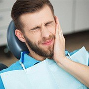 A man holding his mouth in pain.

