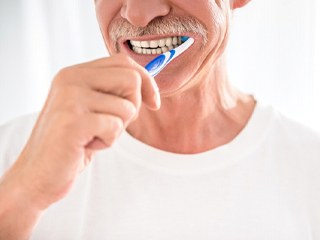 Man preventing dental emergencies in Oklahoma City by brushing teeth