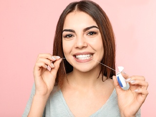 Woman flossing to prevent dental emergencies in Oklahoma City