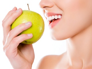 Woman about to bite into a yellow apple