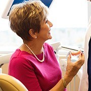 Senior woman holding denture talking to dentist