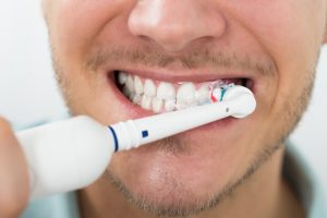 man using an electric toothbrush